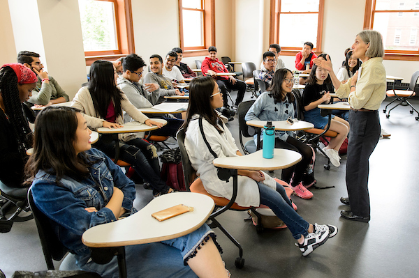 Classroom with international students sitting at desks with instructor standing, facing them